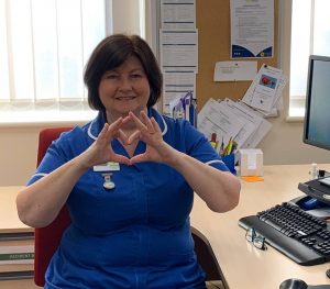 A Primrose Hospice nurse makes a heart shape using her hands.