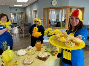 Primrose Hospice nurses dressed in yeloow feather boas, hats and wigs, hold a tea party to promote Yellow Week.