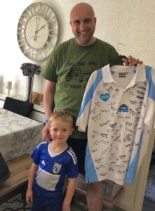 Leighton Webster with son Noahholding a Birmingham City football shirt signed by nurses from the hospital which cared for him at The Alexandra Hospital, Redditch.