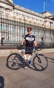 A man stood outside Buckingham palace with a bike, ready to start Ride London.