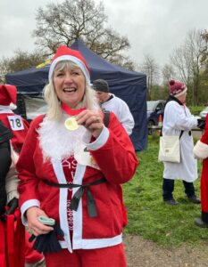 Woman in a Santa suit with a medal after finishing Santa Fun Run