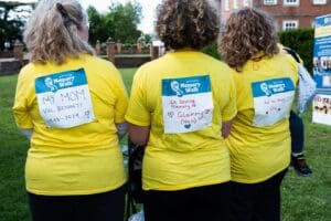 Three Primrose Memory Walk supporters showing their in memory signs on their backs.