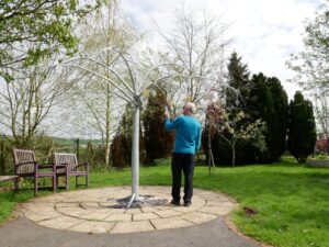 A man stood in the Primrose Hospice garden looking at the Memory Tree