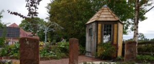 A garden with a wooden lodge in the background.